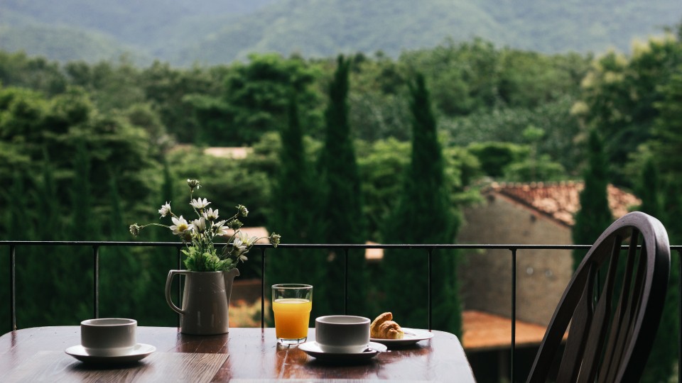 Uma mesa com uma chávena de café e vista para a serra, proporcionando um refúgio tranquilo aos hóspedes que procuram licença de alojamento local - efacont