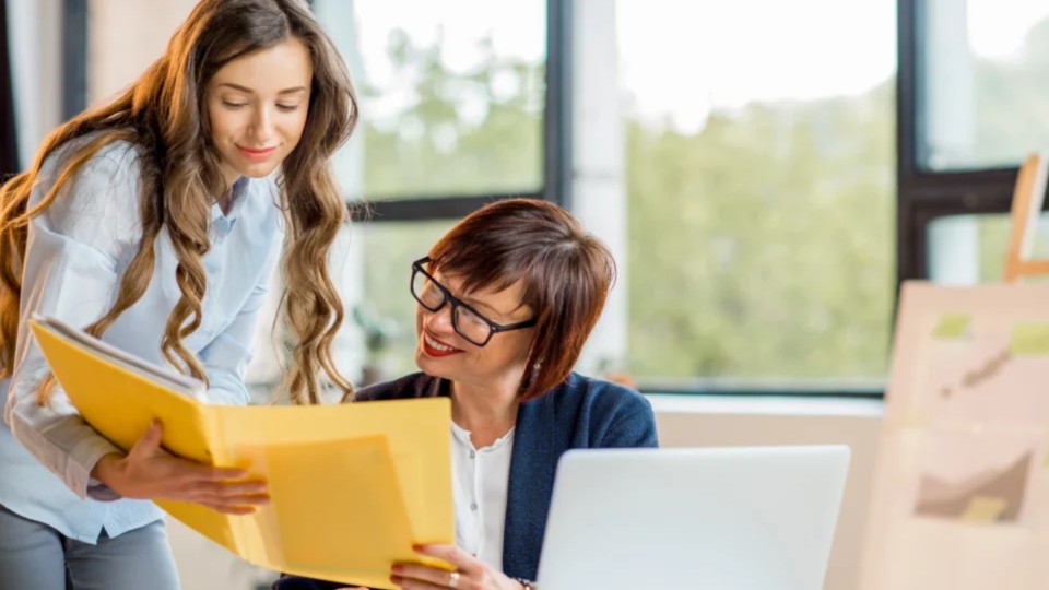 Duas mulheres a analisar uma pasta em um escritório - efacont