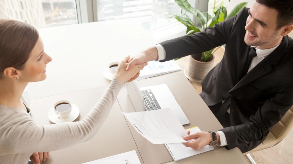 Um empresário e uma mulher apertando as mãos durante uma reunião sobre agenda do trabalho digno no escritório - efacont